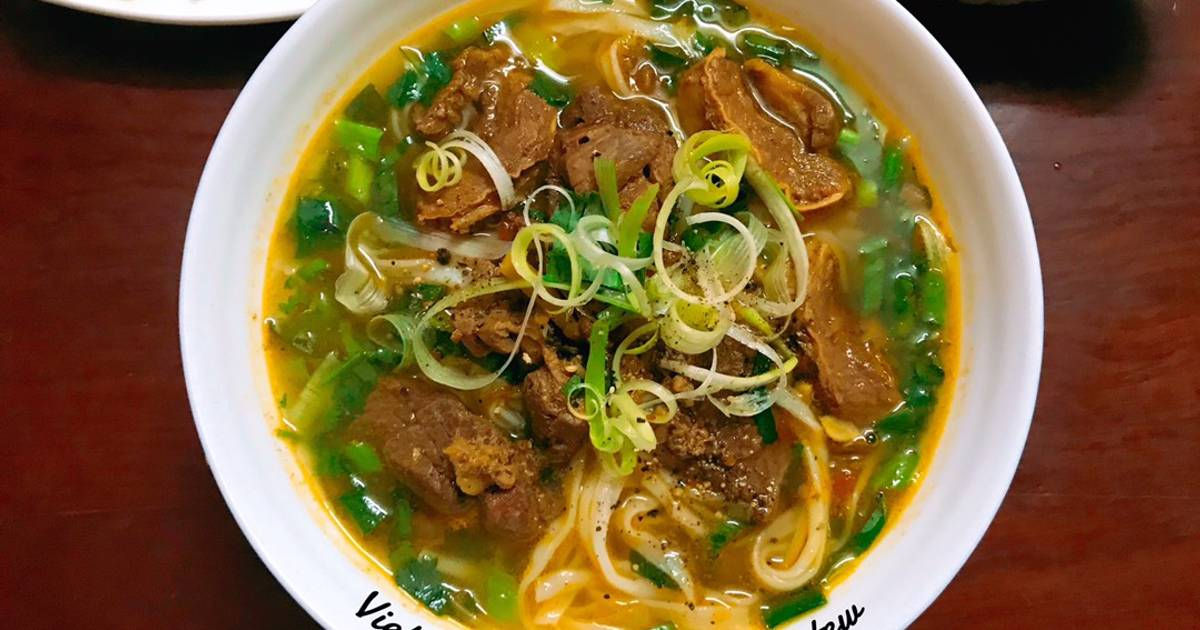 A deep-colored bowl of phở sốt vang with braised beef and fresh herbs