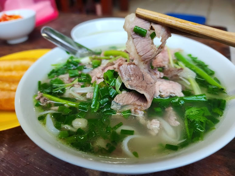 A bowl of traditional phở bò with thinly sliced beef and clear broth