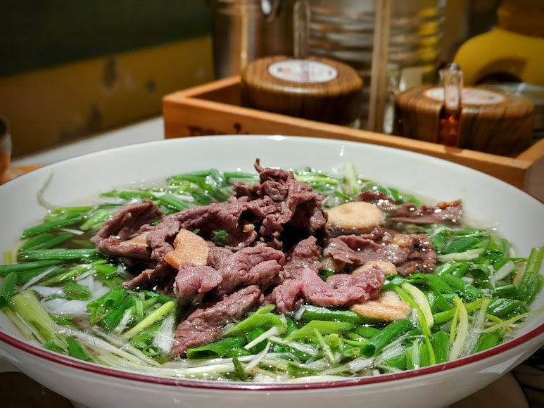A bowl of phở tái lăn with stir-fried beef and a rich broth