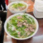 A steaming bowl of Hanoi-style phở with thinly sliced beef and a clear broth